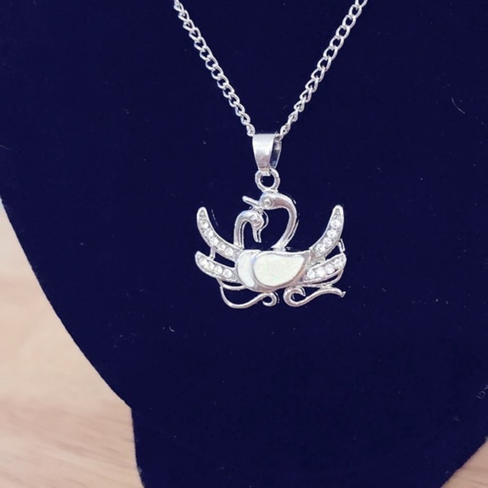 Silver toned double swan necklace. Swans are silver  and white.